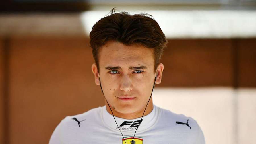 Dino Beganovic poses with the DAMS Lucas Oil Formula 2 car after re-signing for the 2026 season, wearing his Ferrari Driver Academy gear and smiling with the team.