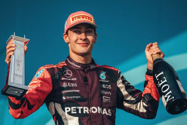A jubilant George Russell on Miami GP podium with champagne and trophy.