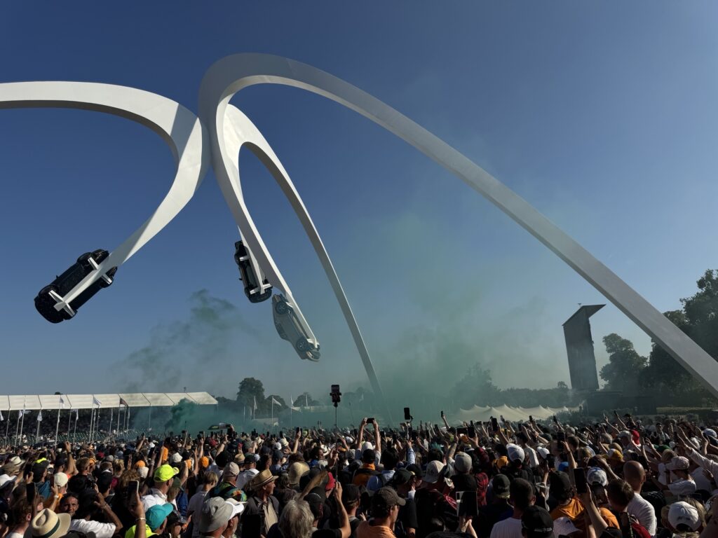 Wide angle image of capacity crowd on Goodwood House lawn with green smoke awaiting Norris' arrival