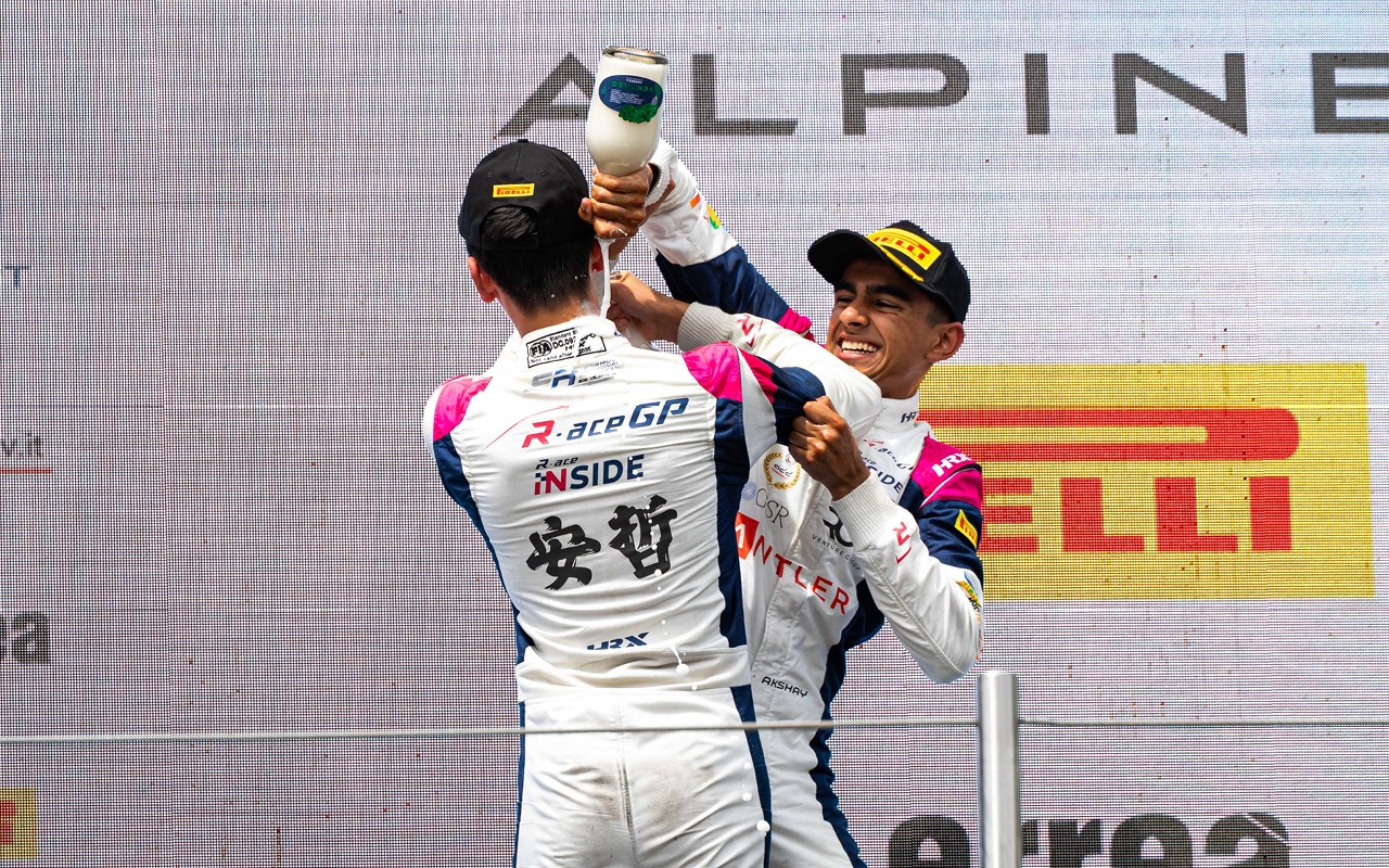 R-ace GP's Akshay Bohra pouring champagne over teammate Enzo Deligny during FRECA Race 1 podium at Imola.